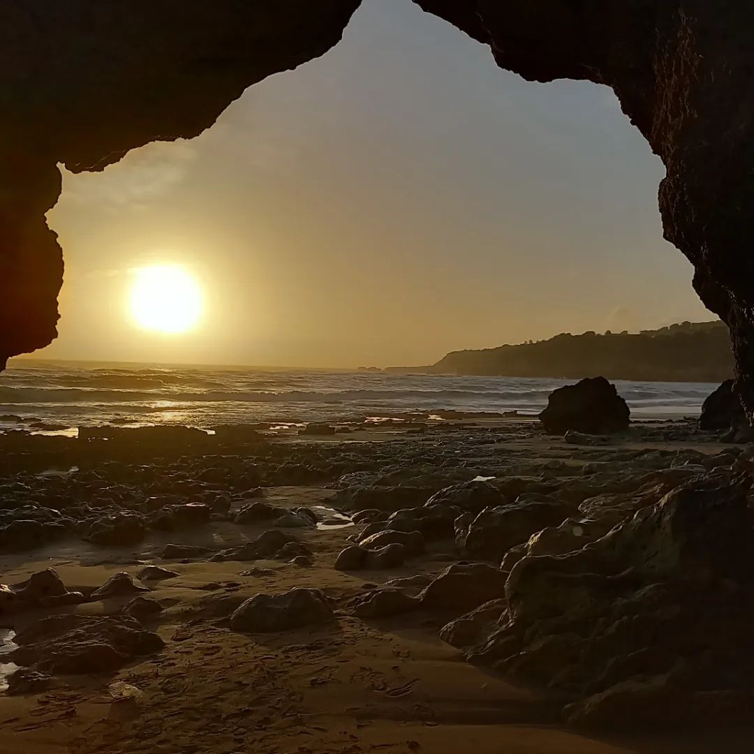 Golden Atlantic sunset framed by a sea-cave arch on an Albufeira beach